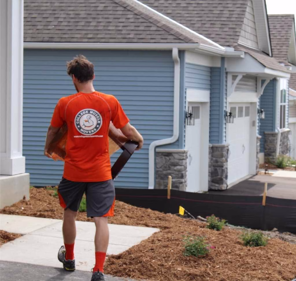 A College Muscle Movers employee carrying furniture into a home in a new development near Woodbury, MN