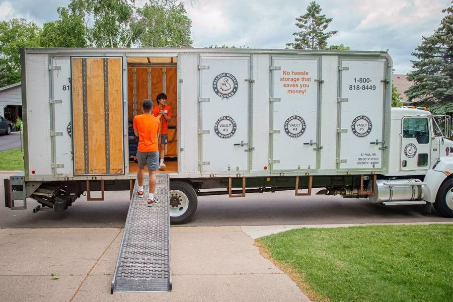 A College Muscle Movers crew carrying furniture into a moving truck at a home near Eagan, MN