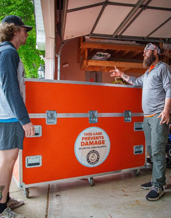 Two College Muscle Movers employees loading a TV into their TV Road Case