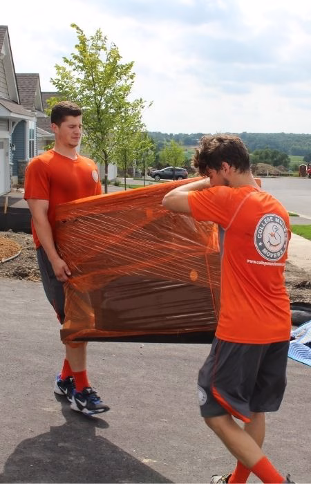 Two College Muscle Movers carrying a sofa into a home near Minneapolis, MN