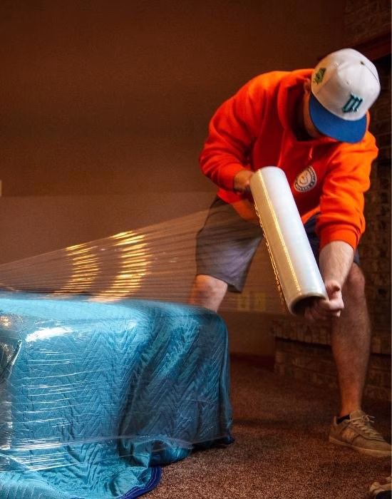 A College Muscle Movers employee prepping furniture for a move