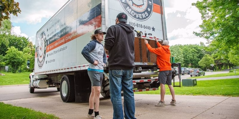 A College Muscle Movers crew greeting a customer in the driveway of a house in the Twin Cities, MN.