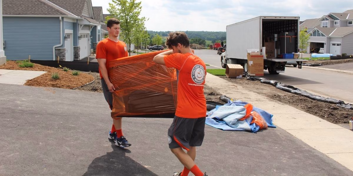 Two College Muscle Movers employees showing how to move heavy furniture during a move near Minneapolis, MN.