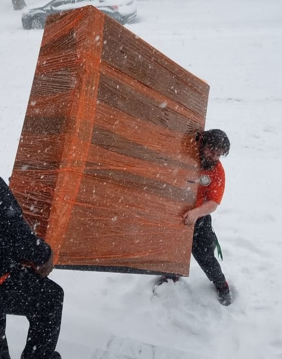 Movers carefully carrying a wrapped piece of furniture to protect it during a cold-weather move